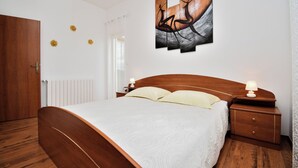 A bedroom with a wooden bed, a nightstand with a lamp, and a wall-mounted artwork. - Apartment Marinko (Marcana)
