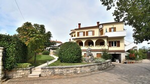 A two-story house with a stone pathway, a statue, and a well-maintained garden. - Apartment Marinko (Marcana)