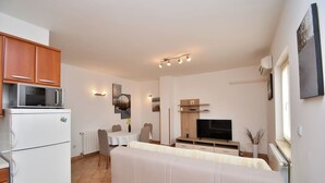 A compact living space with a kitchenette, a sofa, a dining table, and a TV. - Apartment Marinko (Marcana)