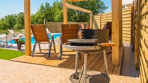 An outdoor patio with a wooden pergola, a barbecue grill, and two lounge chairs. - Apartment Marinko (Marcana)