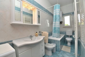 A bathroom with a sink, mirror, towel rack, toilet, and shower curtain. - Apartment Marinko (Marcana)