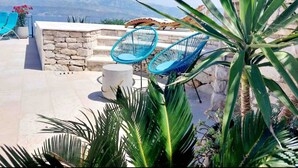 A patio with stone steps, two blue chairs, and a view of mountains. - House Ita (Postira)
