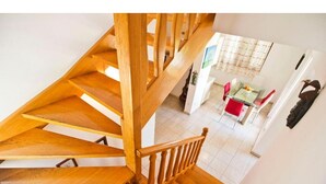 A wooden staircase leading to a dining area with a table and chairs. - Apartment Mana (Split)