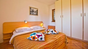 A bedroom with a wooden bed, a nightstand, a wardrobe, and a framed picture on the wall. - Apartment Mana (Split)