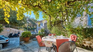 En uteplats med ett bord för två personer, omgiven av krukväxter och en stenmur.