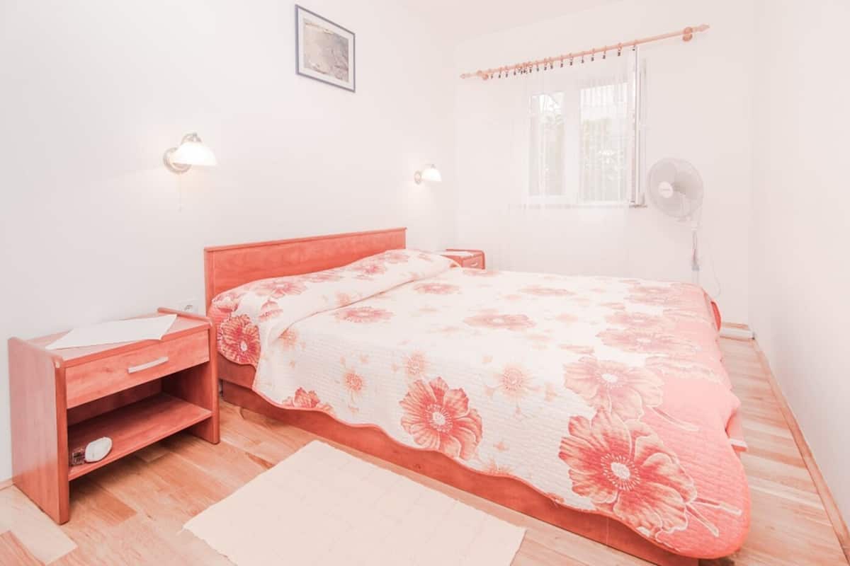 A bedroom with a bed, bedside table, and a desk.
