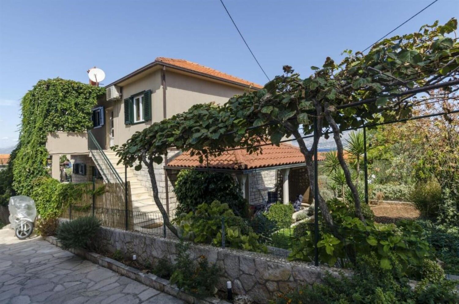 A two-story house with a stone wall and a garden.