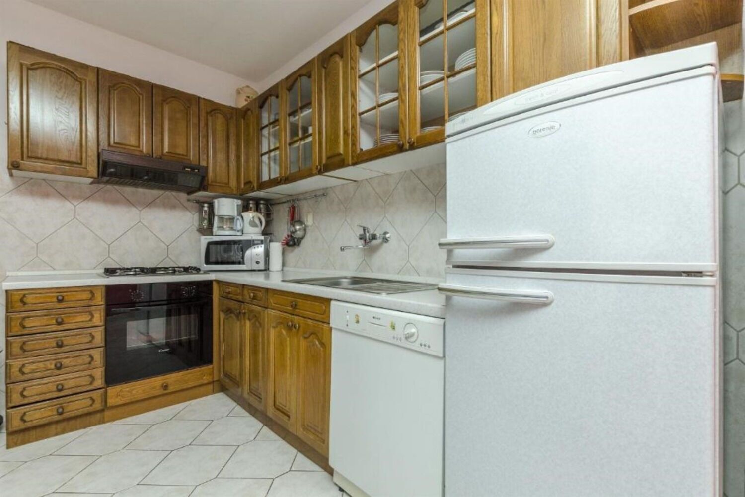 A kitchen with wooden cabinets, a white refrigerator, a stove, a microwave, and a dishwasher.