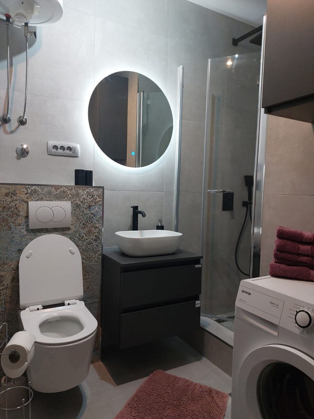 Een moderne badkamer met toilet, wastafel en douche.