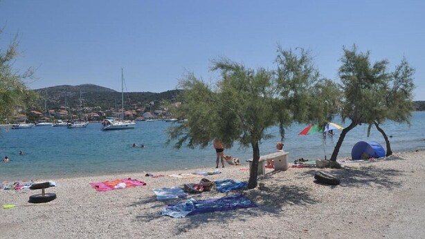 Una playa con barcos, tiendas de campaña y gente.