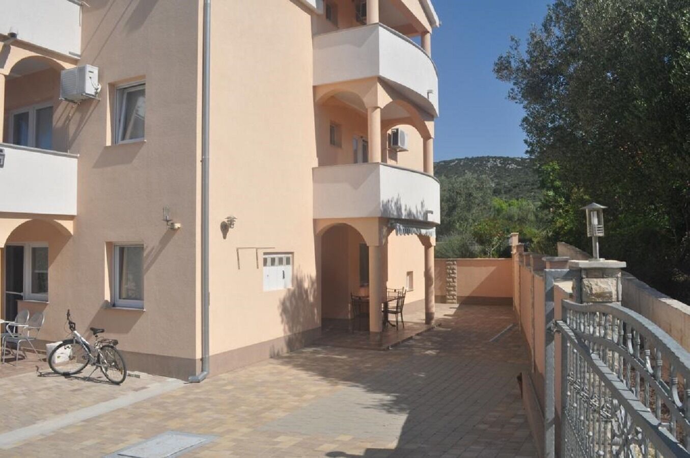 Un edificio de varios pisos con balcones, un patio empedrado y una bicicleta estacionada afuera.