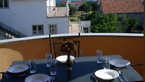 Mesa lista para dos con vista a un pueblo costero y colinas al fondo.