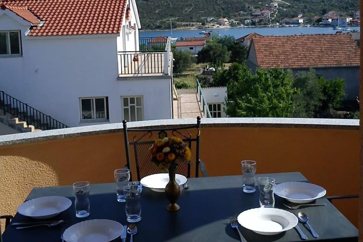 A table set for two with a view of a coastal town and hills in the background.