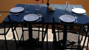 Mesa de comedor al aire libre con vista a un edificio blanco de tejado rojo.