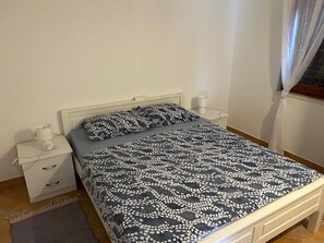 Un letto singolo con una coperta a motivi, un comodino con una lampada e un tavolino da notte con una lampada.