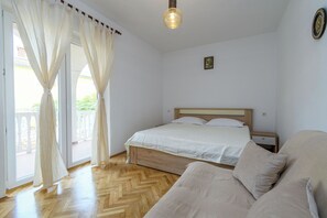 Ein Schlafzimmer mit einem Bett, einem hölzernen Kopfteil, einem Nachttisch, einem Sofa und einer Glasraumtür mit Vorhängen.