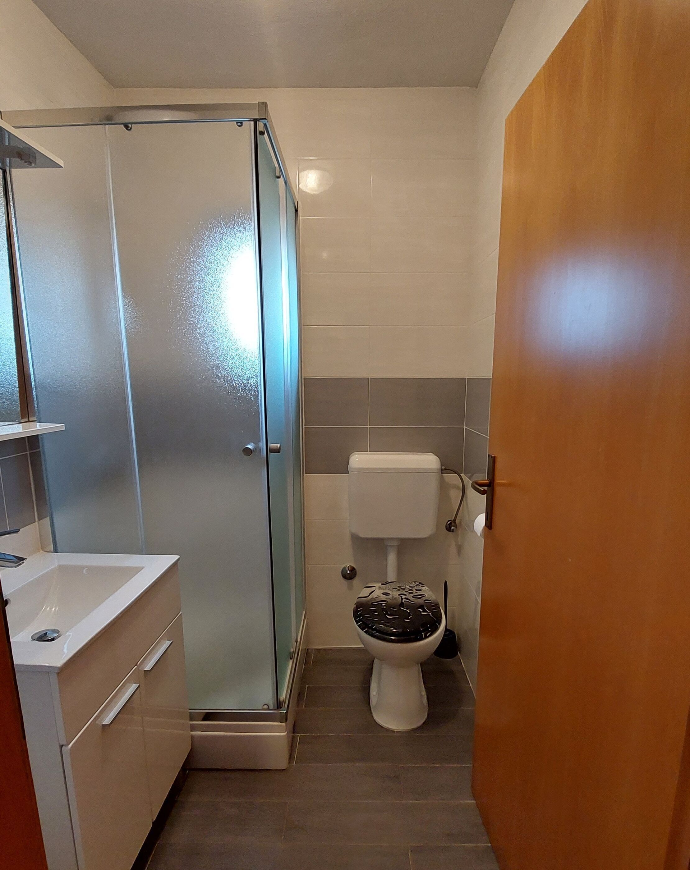 A bathroom with a glass-enclosed shower, a toilet, and a sink.