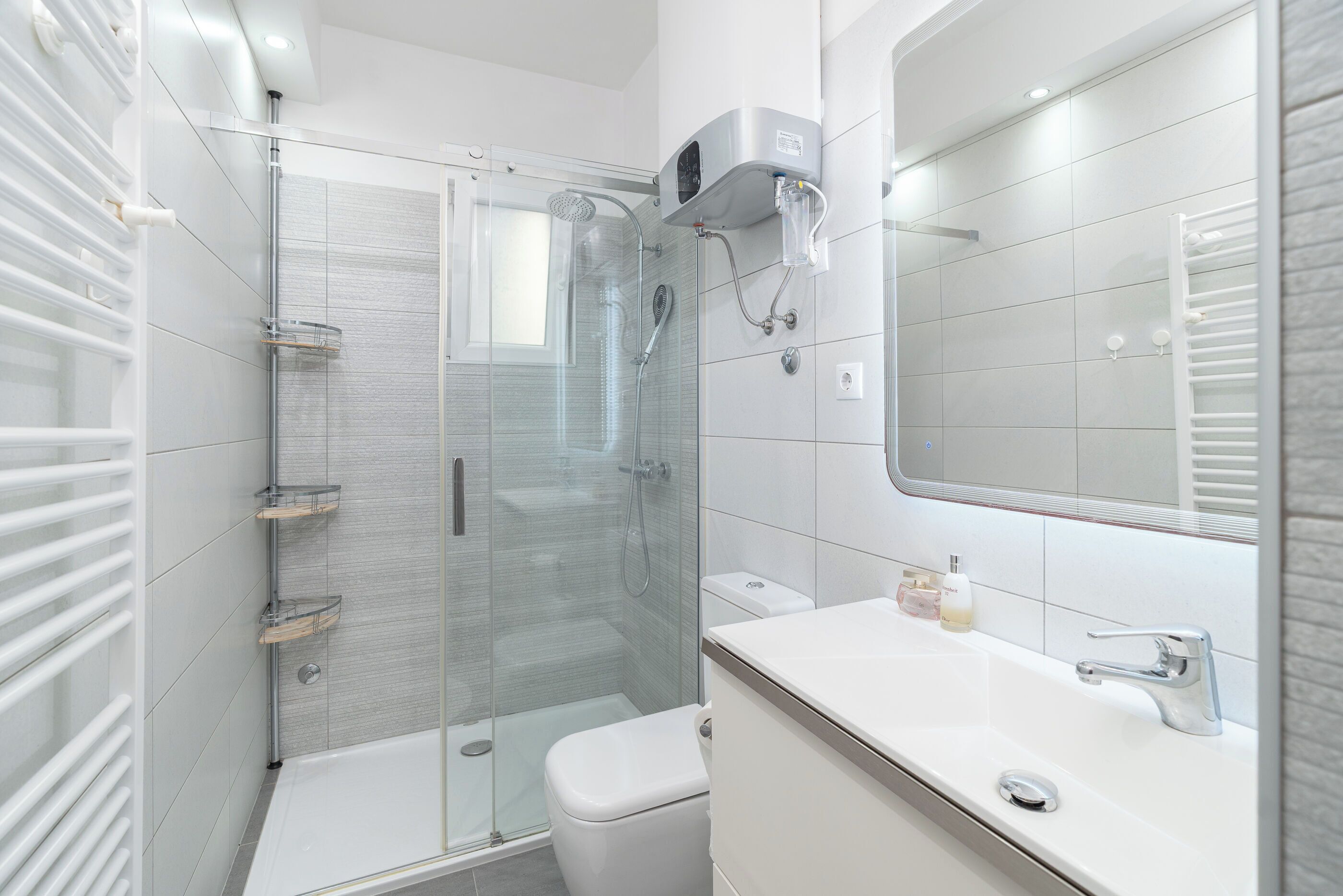 A modern bathroom with a glass-enclosed shower, a white sink, and a large mirror.