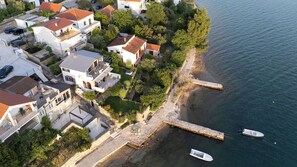 An aerial view of a coastal residential area with houses, a pier, and boats. - Apartment Vlatkica (Jasenice)