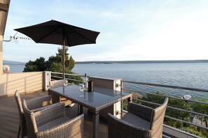 A balcony with wicker furniture, a glass table, and an umbrella. - Apartment Vlatkica (Jasenice)