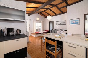 A modern kitchen with a dining area, wooden beams, and a painting on the wall. - Apartment Vlatkica (Jasenice)