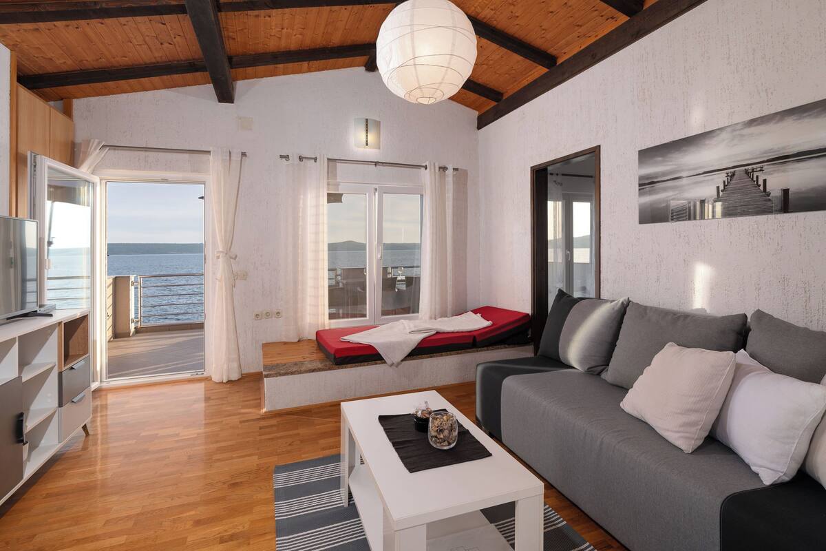A modern living room with a sofa, a coffee table, and a view of the sea.