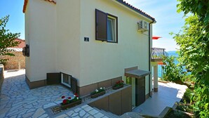 A building with a stone-paved entrance, a small window with shutters, and a balcony with a view of the sea. - House Sreca (Okrug)