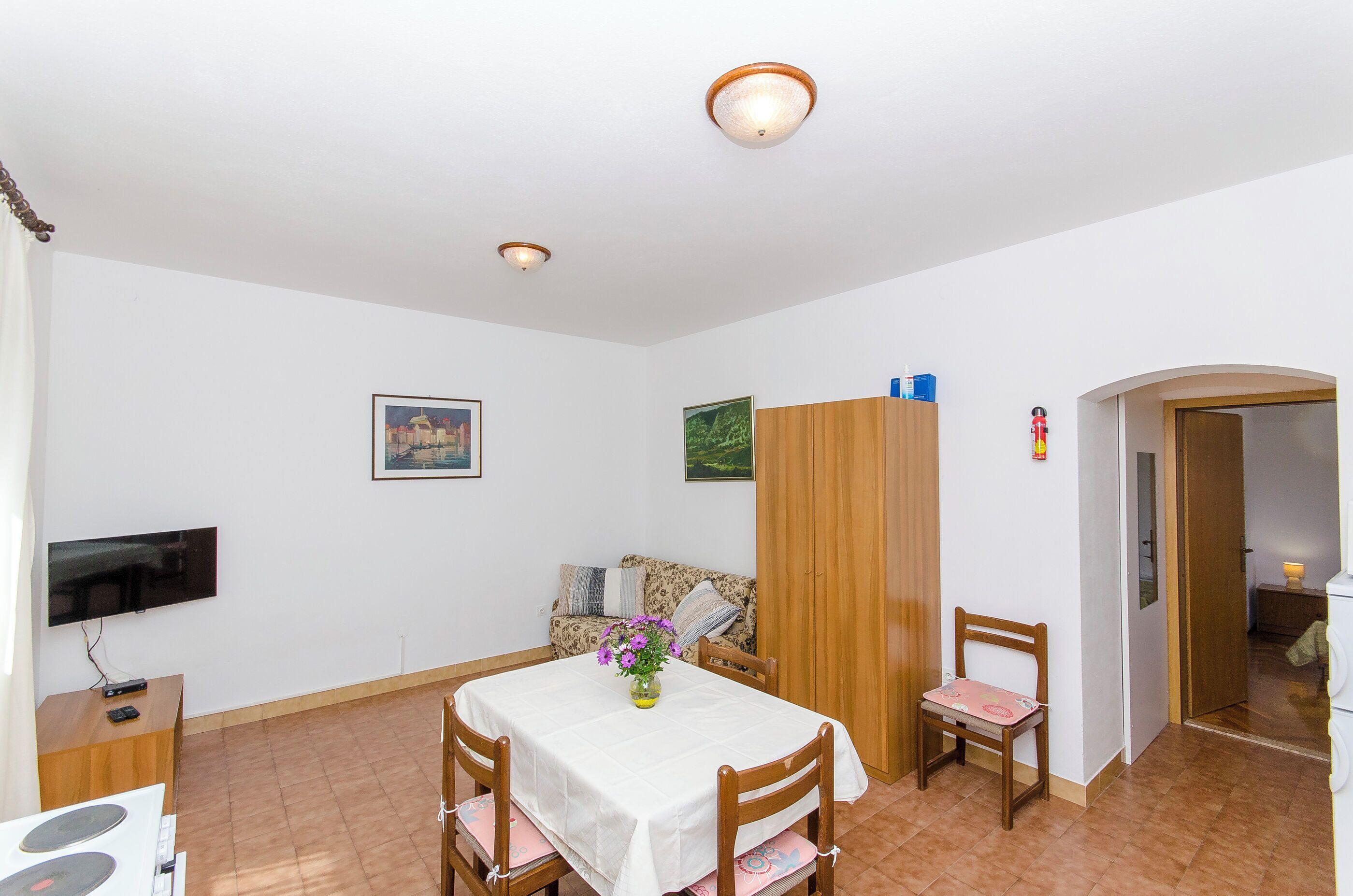 Ein Essbereich mit Tisch, Stühlen, einem Fernseher und einem Schrank.