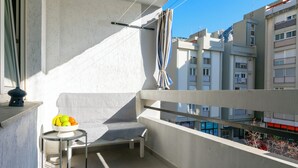 A balcony with a sofa, a small table with fruit, and a view of buildings. - Apartment Jozo (Omis)