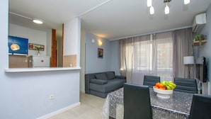 A modern living room with a dining area, featuring a sofa, a dining table with chairs, and a fruit bowl. - Apartment Jozo (Omis)