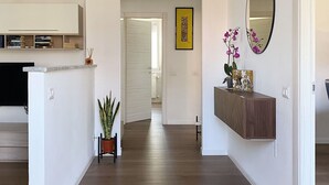 Cozinha moderna com armários brancos, bancada de madeira e um vaso com planta.