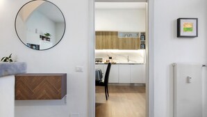 Cozinha moderna com armários brancos, bancada de madeira em padrão herringbone e uma cadeira preta.