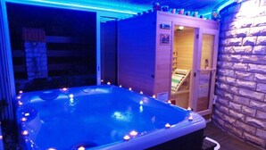 Ein Whirlpool mit Steinwand und Holzterrasse.