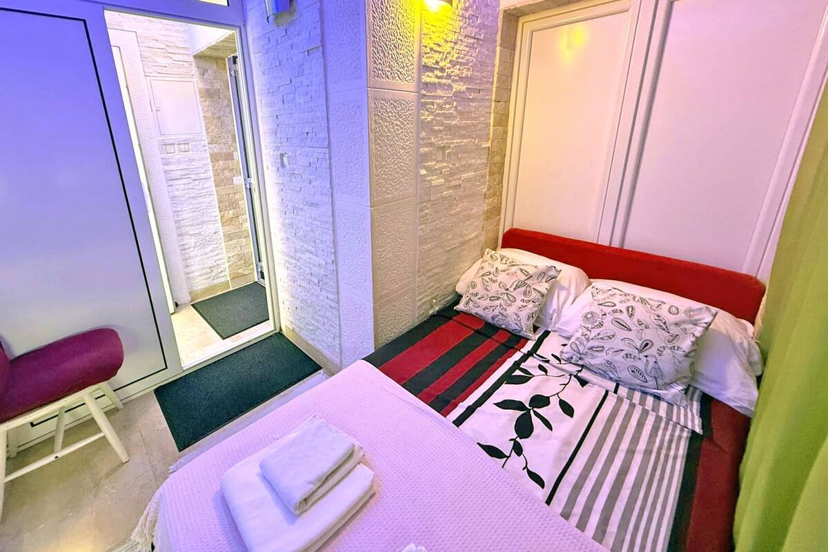 A small, cozy bedroom with a bed, pillows, and a chair.