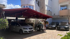 A residential building with a covered parking area, a brick wall, and a carport. - Apartments Dali (Nin)
