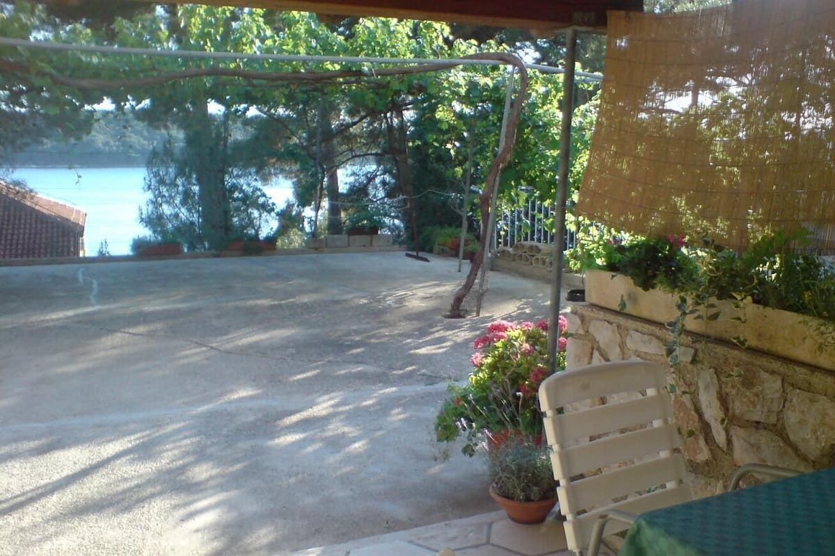 A covered outdoor area with a patio table and chairs, a stone wall, and potted plants.