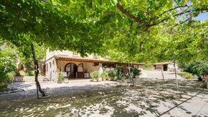 A stone building with a tiled roof, a covered patio, and potted plants. - Apartments Pero (Mali Losinj)