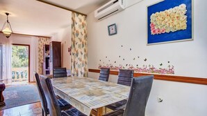 A dining area with a long table, black chairs, and a patterned tablecloth. - Apartments Pero (Mali Losinj)