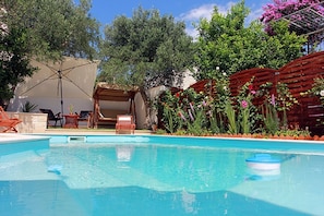 Ein Swimmingpool mit Liegestühlen und einer Pergola mit Blumen.