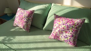 Un llit amb llençols verds i dos coixins florals.