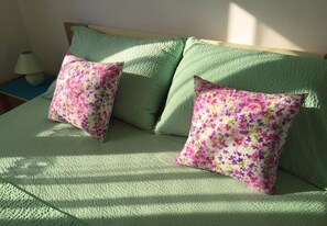A bed with green bedding and two floral pillows. - Apartment Mir (Tisno)