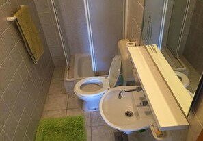 Et badeværelse med toilet, håndvask og brusebad.