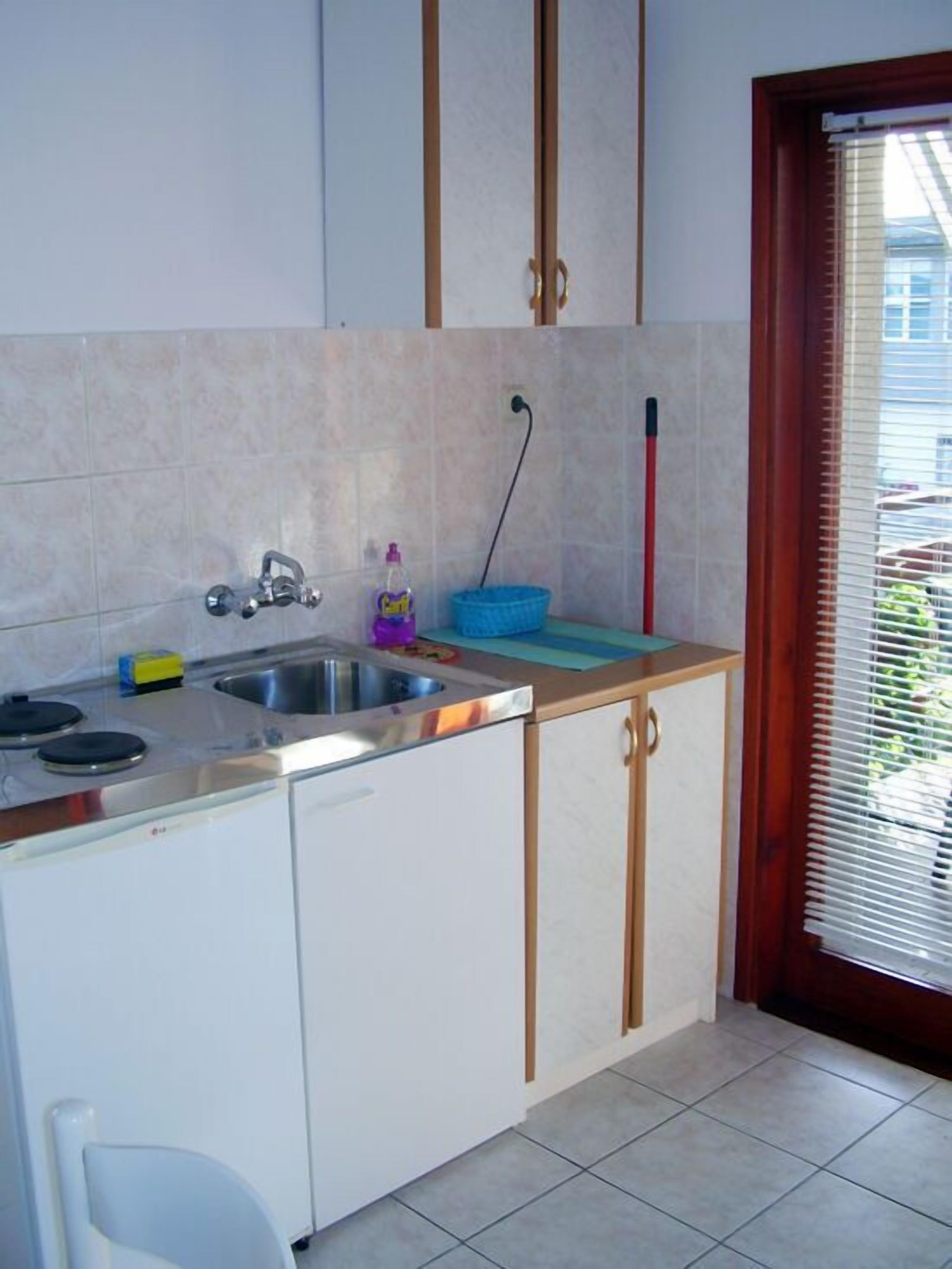 A compact kitchen with a sink, stove, and cabinets.