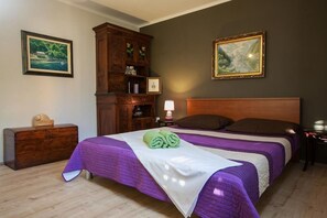 A bedroom with two beds, a wooden dresser, and a cabinet with framed pictures. - Apartment Alta (Makarska)
