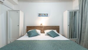 Un lit bien fait, avec une tête de lit en bois, deux oreillers et une couverture de couleur turquoise.