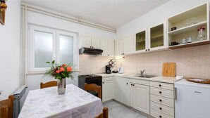 Une cuisine de taille réduite, avec des meubles blancs, une cuisinière, un évier et un réfrigérateur.