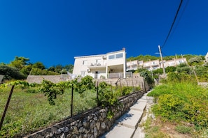 Ein zweistöckiges Gebäude mit einem Balkon, einer Steinmauer und einem Weg, der dorthin führt.