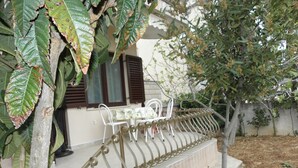 Ein Haus mit überdachter Außenveranda, einer Treppe und einem Baum.