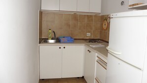 Eine kompakte Küche mit weißen Schränken, einer Spüle, einem Herd und einem Kühlschrank.