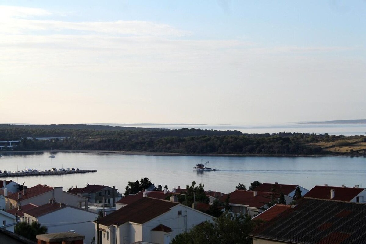 A coastal town with residential buildings, a marina, and a calm body of water.